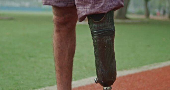Revealing amputee athlete with prosthetic leg standing outside. Portrait of person with missing leg disability