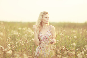 Fototapeta na wymiar romantic girl posing in a summer field dress