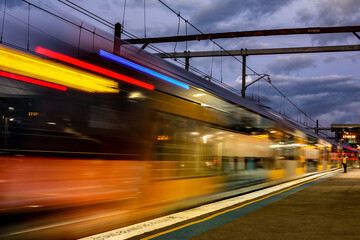 Obraz premium Fast train with motion blur, lone man stands on platform