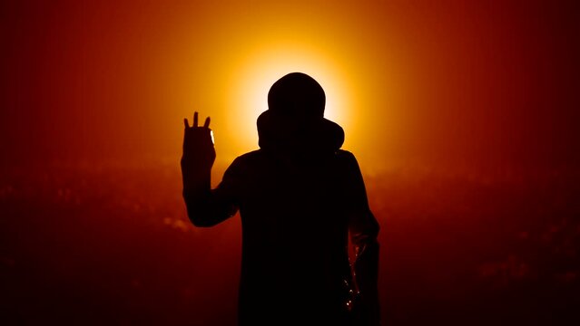 Silhouette of alien waving hand - hello on orange background. Humanoid on extraterrestrial planet. UFO, fantasy, futuristic, fiction concept.