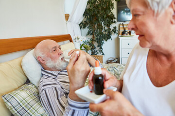 Nurse distributes medication to old man in bed