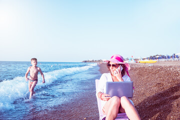woman smart working on the beach with phone and laptop.