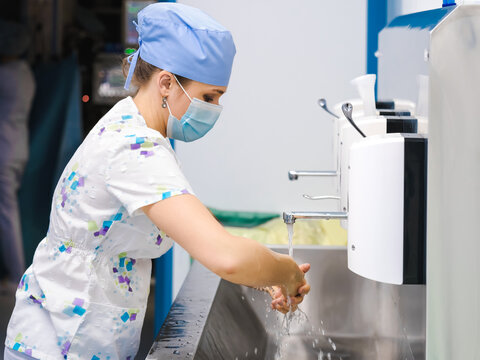 A young female surgeon washes and disinfects her hands before starting surgery.