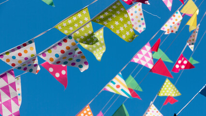 Obraz premium Banderines triangulares de fiesta de colores sobre cielo azul