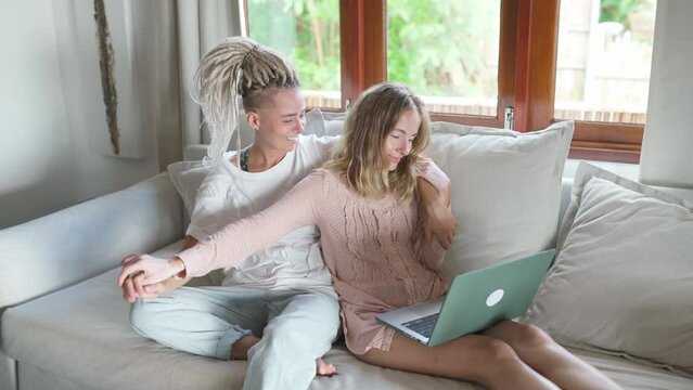 Two young women sitting on a couch and looking in laptop
