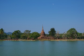 Old temples and pagodas surrounded by water in Sukhothai Historical Park