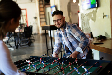 Colleagues having fun at work. Businessman and businesswoman playing table soccer