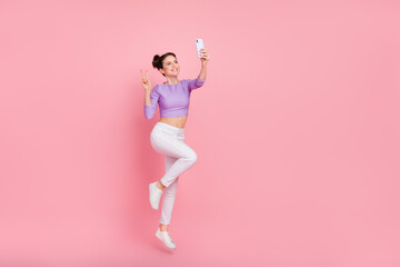 Fototapeta na wymiar Full length body size view of lovely trendy girl jumping taking selfie showing v-sign isolated over pink pastel color background