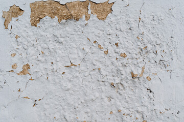 Textured wall. Peeling plaster on the white wall. Aged wall covering. Textured surface in the surrounding environment. Renovation required