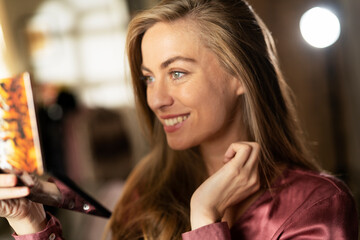 Young woman applying makeup on face at home. Beautiful girl is getting ready to go out