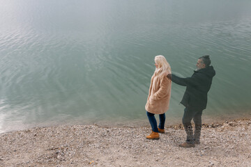 Lonely woman standing by the lake with ghost of a man standing behind her with hand on her...