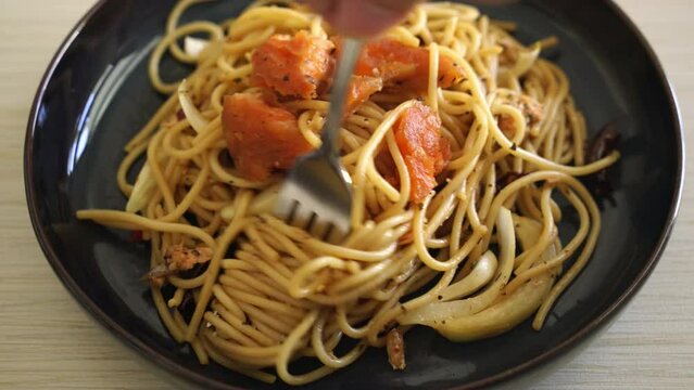 fork rolling stir-fried spaghetti with salmon and dried chilli - fusion food style