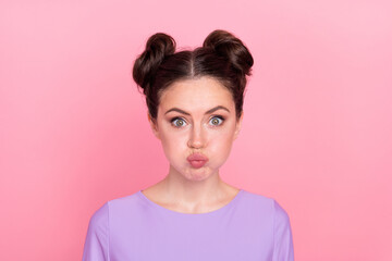 Portrait of attractive funny girl blowing cheeks fooling tease isolated over pink pastel color background