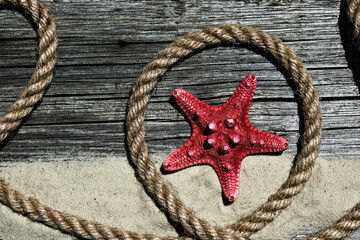 Fototapeta na wymiar Dried red starfish on the sea sand on a wooden background. Flat lay, place for text.
