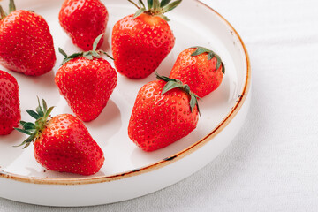 A few ripe juicy strawberries in a plate on a white background close-up