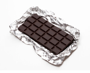 Dark chocolate bar on alluminium confectionery paper on white background.