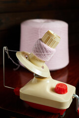 Mechanical yarn winder or reel while rewinding thread. Close-up, selective focus