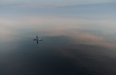 Fototapeta na wymiar SUP surfer floats in an open calm sea. Aerial view
