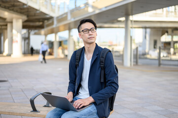ベンチに座りパソコン作業をする男性