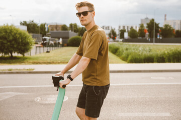 Young man unlocks an e-scooter with his mobile phone. Electric scooter new way city mobility. Green...