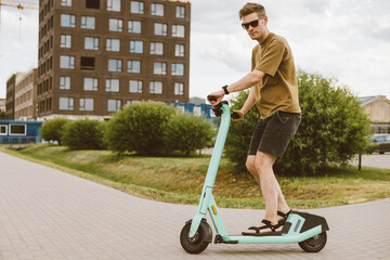 Young man unlocks an e-scooter with his mobile phone. Electric scooter new way city mobility. Green...