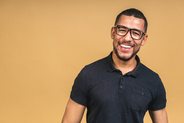 Portrait of a cheerful smiling young african american black man standing isolated over beige background.