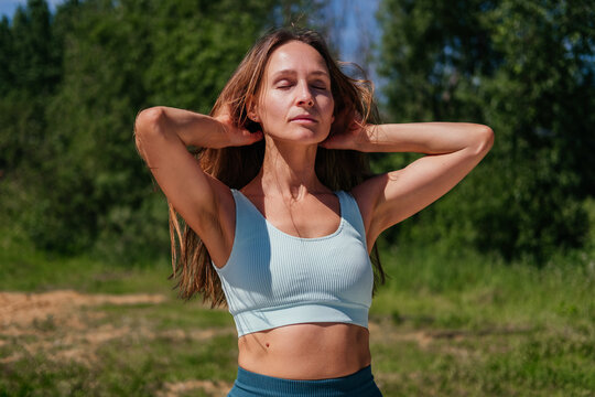 Middle aged woman in sportswear standing outdoor enjoying sun. Fitness woman warming up