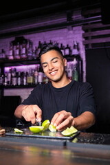 smiling young boy behind a bar bar cutting pieces of lime
