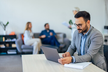 Male boss working at the co-working space, employers sitting in the background.