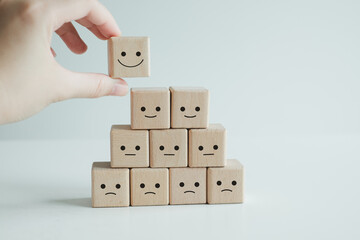 Customer service evaluation and satisfaction survey concepts. The client's hand picked the happy face smile face symbol on wooden blocks.