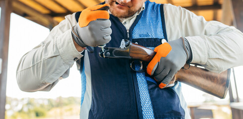 Adult trapshooter lubricates his gun before starting to shoot.