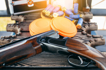 Shooting sports equipment for trap shooting on wooden table. Air-gun and bullets.
