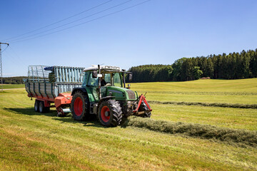 Obraz premium The combine pours silage into the tractor-trailer in the field. Preparing animal feed for the winter.