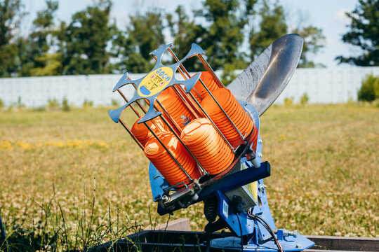 Plat machine with orange shooting plate for shooting-ground training on field with grass