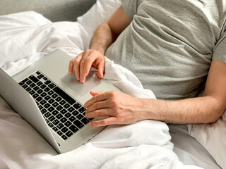 Middle aged adult man using laptop at home In bed vibes white bedsheets Alone Early morning working. freelancer, freelance job, using technology, using social media, watching movie, checking news,