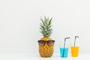 Ripe pineapple in sunglasses and cocktails on a white background. Summer vacation. Hello summer