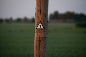 High voltage sign on a wooden pole. The concept of expensive electricity. Rising energy prices. Inaccessible electricity as a result of high prices