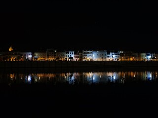 Fototapeta premium View of the city of Seville at night. With the Guadalquivir river in the foreground and the Triana bridge and Seville buildings in the background. nightlife concept. europe travel and ancient architec