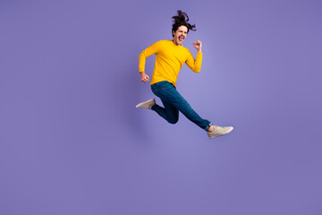 Fototapeta na wymiar Full length photo of delighted astonished man jumping raise fist celebrate success isolated on violet color background