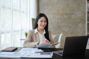 Young business woman is working on paperworks and laptop in office space.