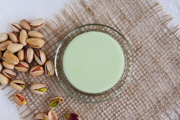 Pistachio milk in a glass on a burlap. This milk is a great source of antioxidants, phytosterols, and heart healthy fats