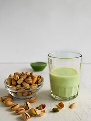 Pistachio milk in the glass and pistachio paste  on the white background. This milk is a great source of antioxidants, phytosterols, and heart healthy fats
