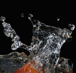 Isolated splashes of water on a black background. The fruit falls into the water.