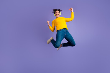 Fototapeta na wymiar Full body of energetic overjoyed guy jumping raise fists shout yes rejoice isolated on purple color background