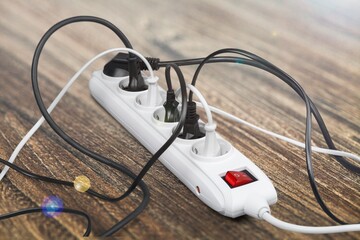 Unplugged electric appliance plug over switched off white power strip on the floor. Increasing the energy costs, heating costs, save electricity concepts.