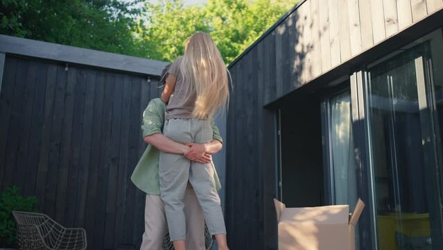 Cheerful young couple celebrating moving in their new tiny house in woods. Conception of moving and sustainable living.