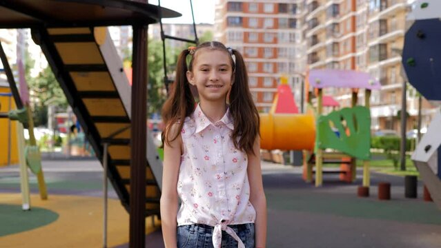 A happy 10-year-old girl on the background of a childrens playground.