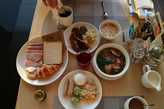 Brunch Dining Scene With Multiple Meals On The Table, Coffee, Toast, Ham, Bread, Rice, Pasta, Fried Rice, Etc.