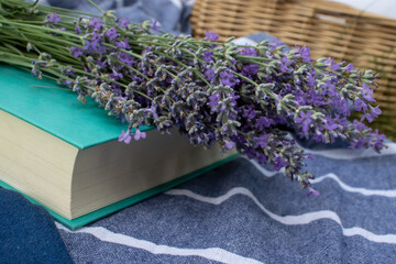 Bunch of lavender flowers and a book on a fabric background outdoors. Relaxing in nature, summer...
