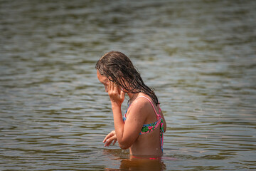 Naklejka premium A little girl splashes in a pond during the day.